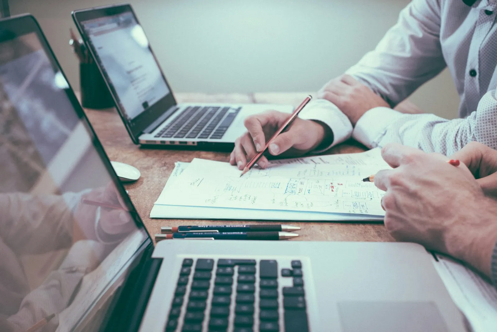 Professional reviewing documents and planning work at a desk with a laptop